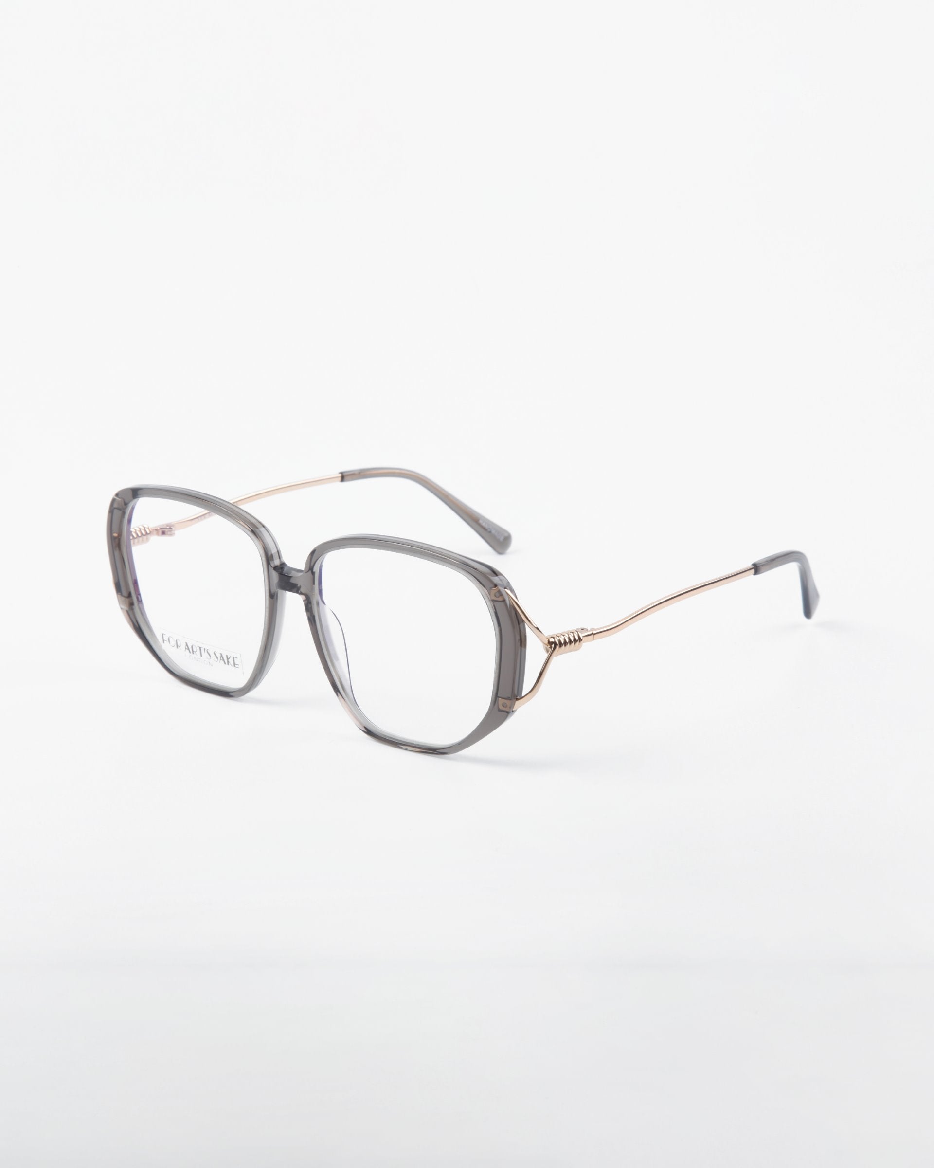 A pair of stylish **Remix** prescription glasses by **For Art&#39;s Sake®** with a gray, translucent frame and thin gold temples, photographed against a plain white background. The lenses are clear, offering both UV protection and a blue light filter. The design exudes a modern and sophisticated look.