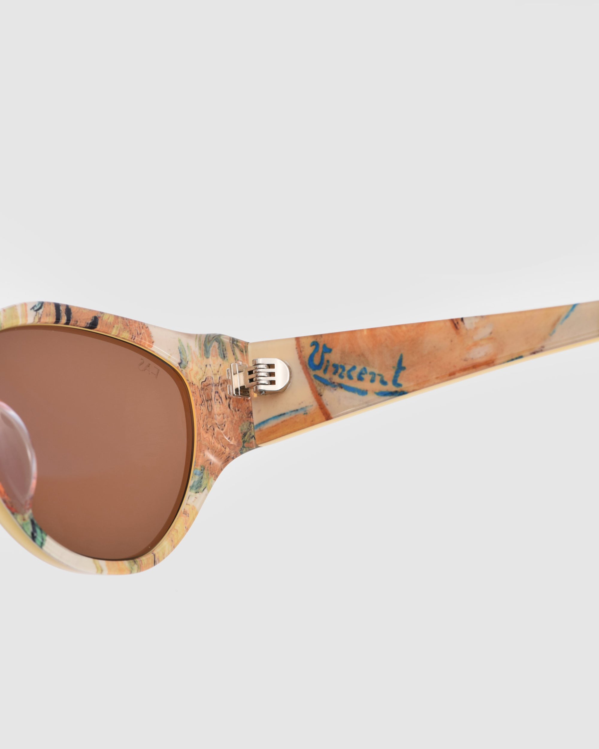 Close-up of For Art&#39;s Sake® Vincent Van Gogh limited edition cat-eye sunglasses with a multicolored artistic frame, &quot;Vincent&quot; in blue on the arm, and brown-tinted lenses.