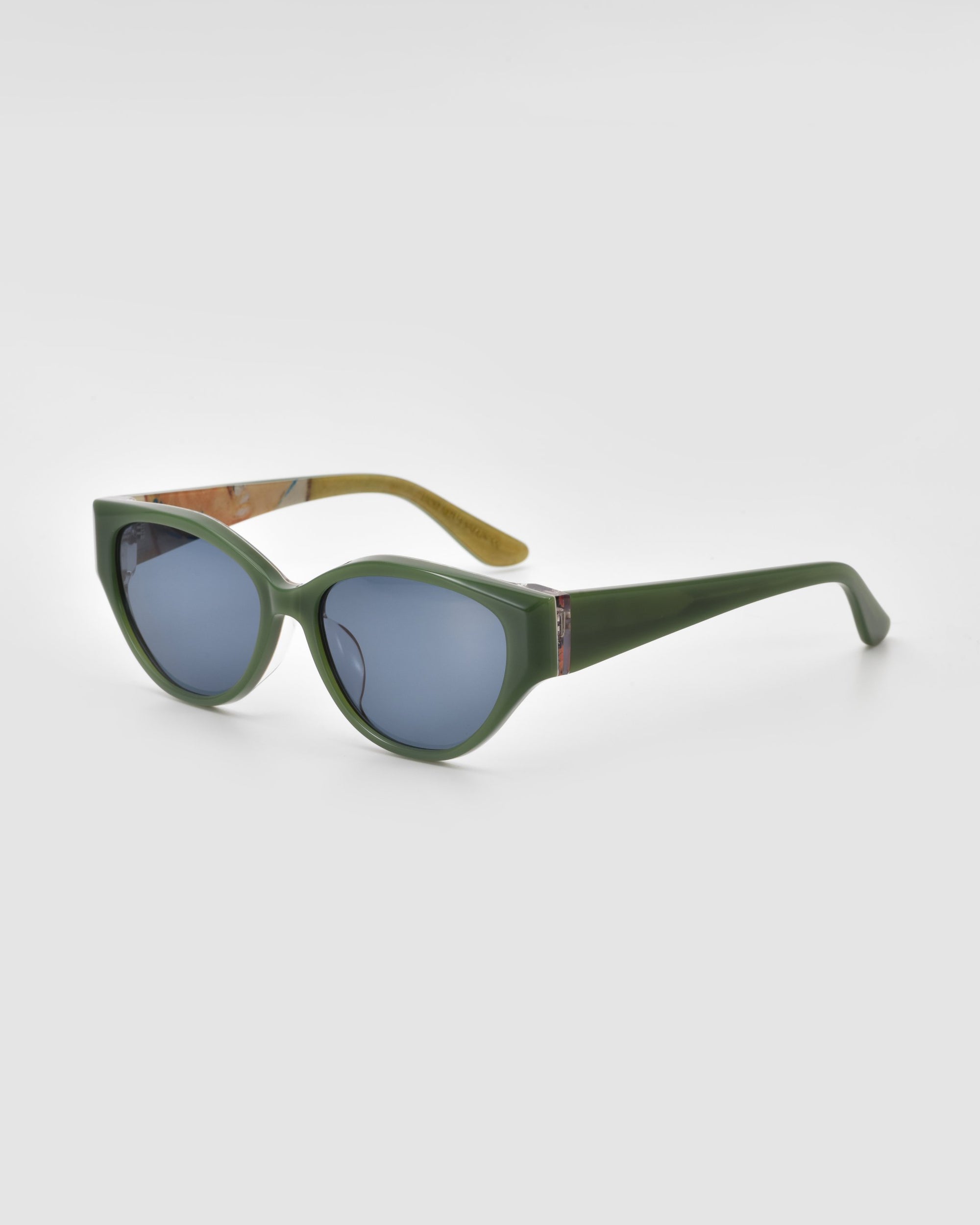 The For Art's Sake® Vincent Van Gogh green oval cat-eye sunglasses feature thick frames and blue-tinted lenses, displayed at an angle on a light gray background—an eye-catching choice for any eyewear collector.