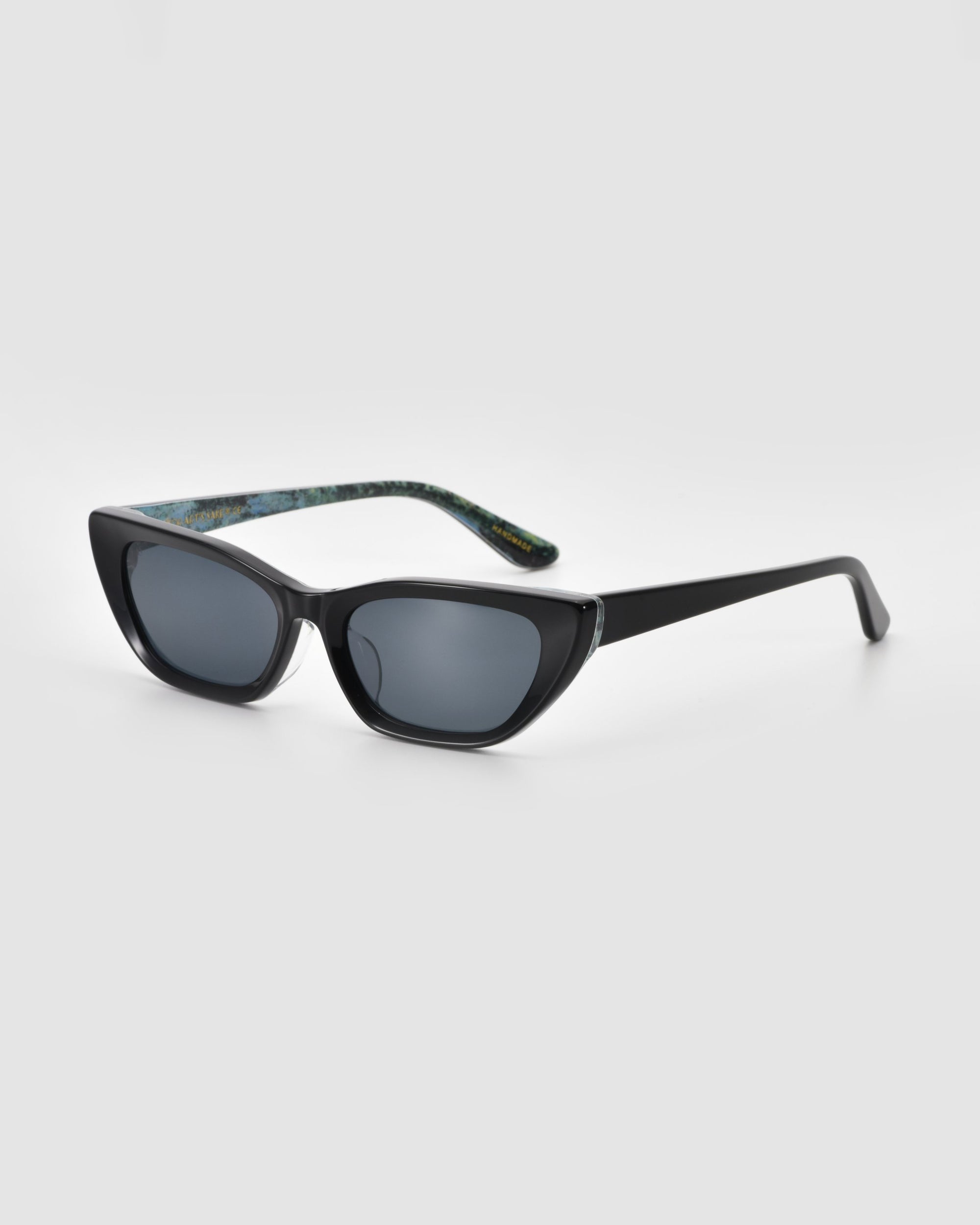 For Art's Sake® Claude Monet limited edition black cat-eye sunglasses feature dark tinted lenses and patterned inner arms, shown on a plain light gray background.