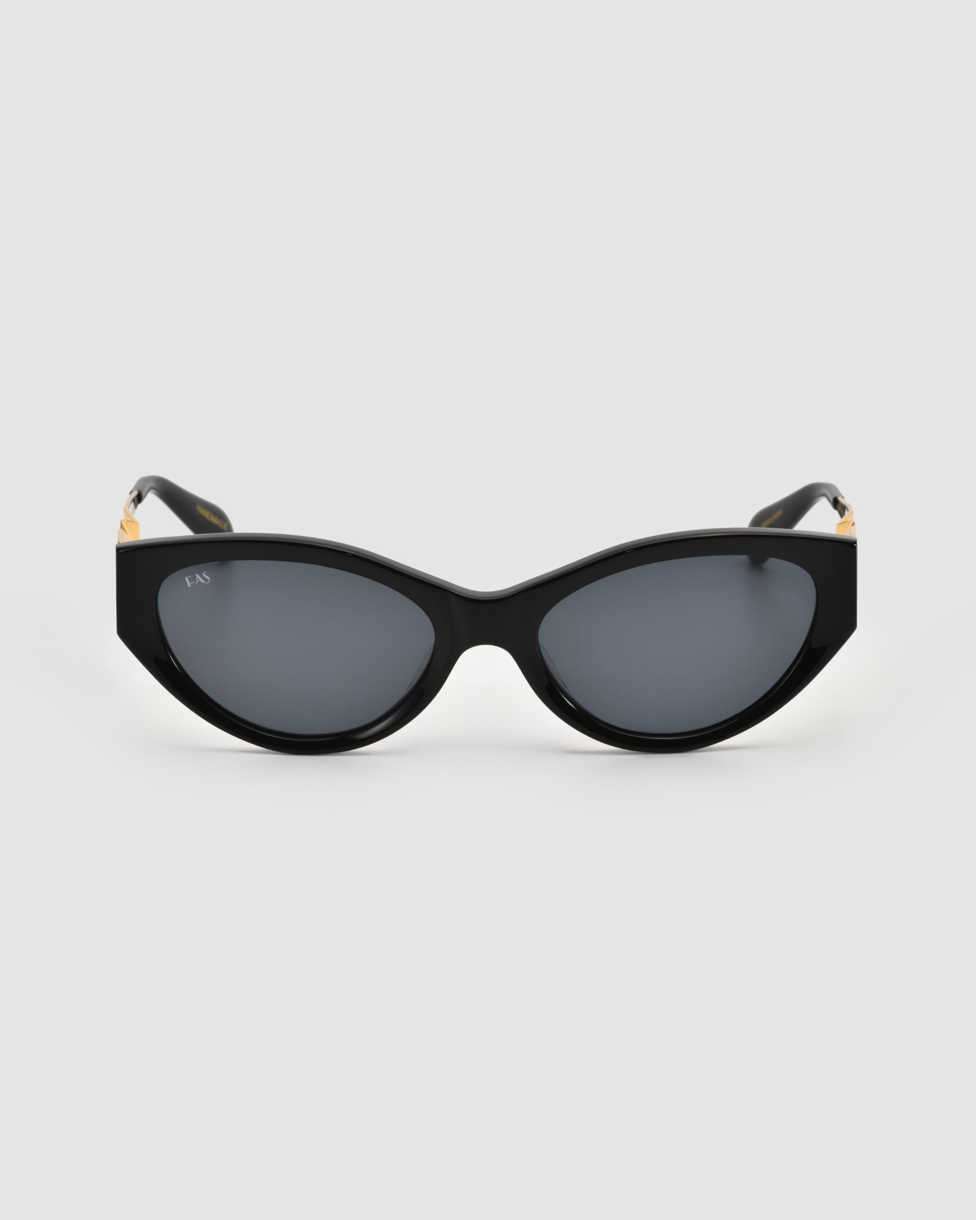 For Art’s Sake® Unfold sunglasses: black sculptural cat-eye frames with dark tinted lenses, gold hinge accents, and a glossy finish, shown on a plain light grey background.