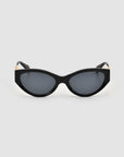 For Art’s Sake® Unfold sunglasses: black sculptural cat-eye frames with dark tinted lenses, gold hinge accents, and a glossy finish, shown on a plain light grey background.