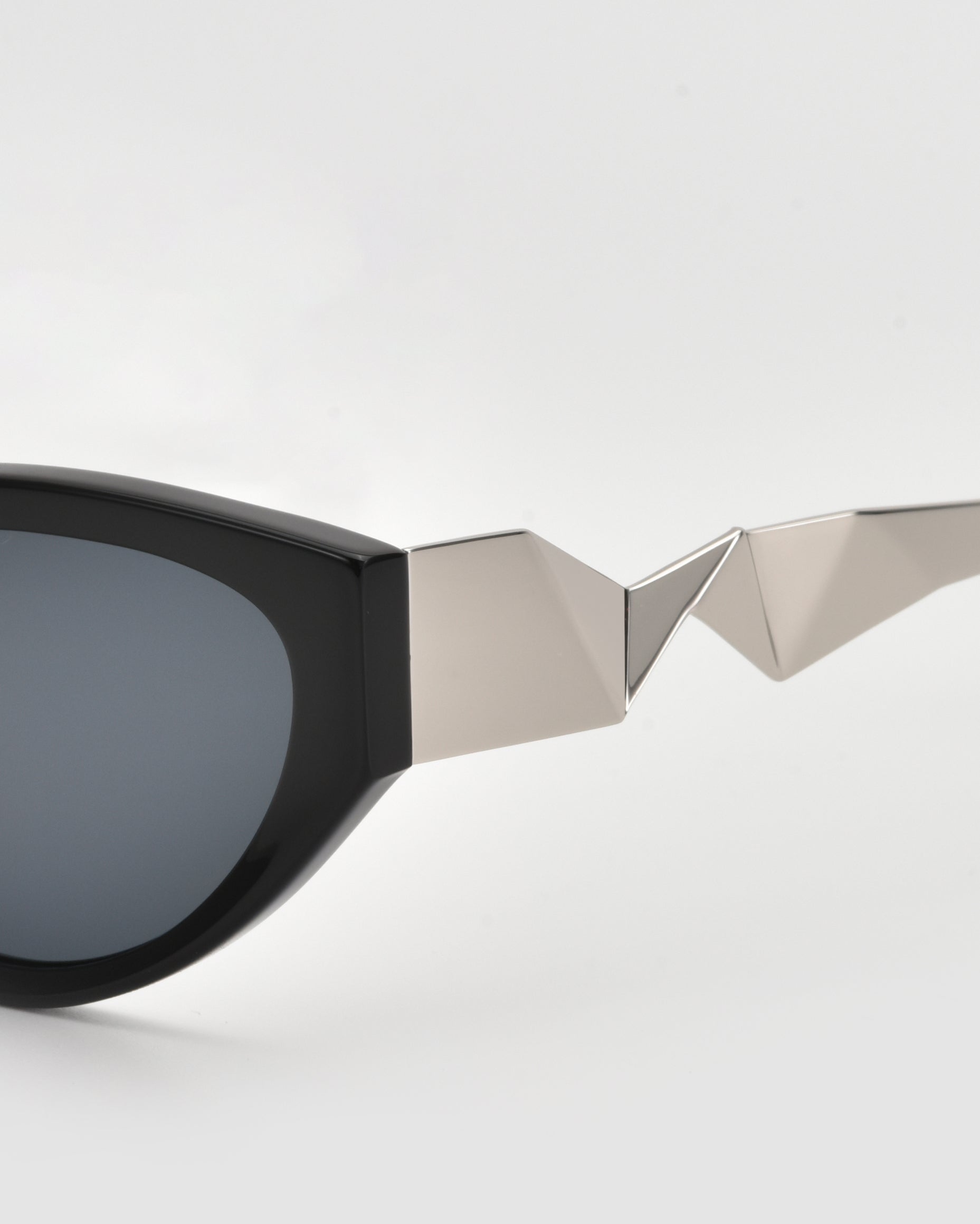 A close-up of For Art’s Sake® Unfold sunglasses, featuring angular silver detailing on the pleated temple, shown against a plain white background.