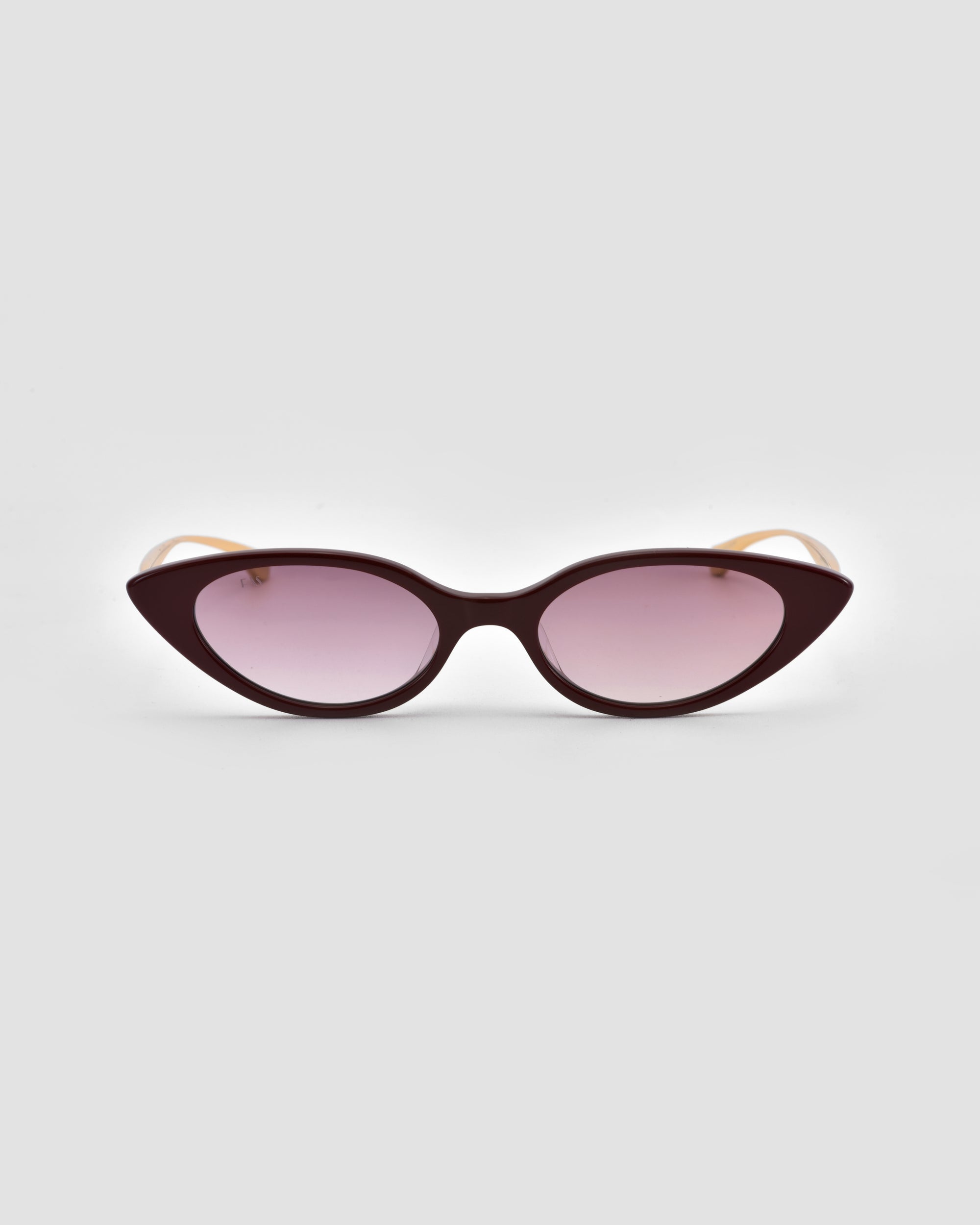 For Art's Sake® Slash cat-eye sunglasses feature dark burgundy frames and gradient purple lenses, offering sculptural flair to modern eyewear and shown against a light gray background.