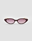 For Art's Sake® Slash cat-eye sunglasses feature dark burgundy frames and gradient purple lenses, offering sculptural flair to modern eyewear and shown against a light gray background.