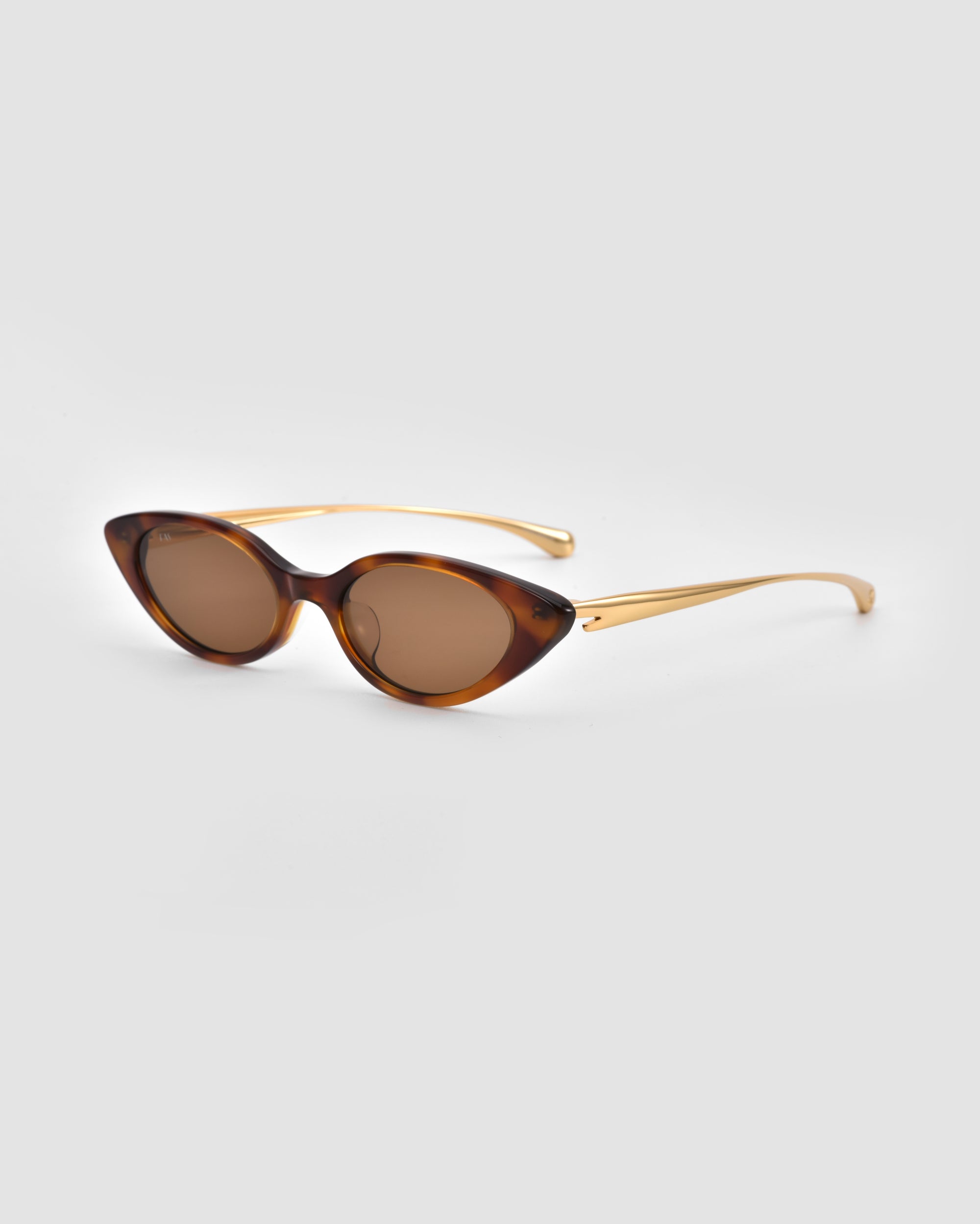 For Art's Sake® Slash cat-eye sunglasses with brown-tinted lenses and a tortoiseshell frame, sculptural curved arms, shown on a light grey background.