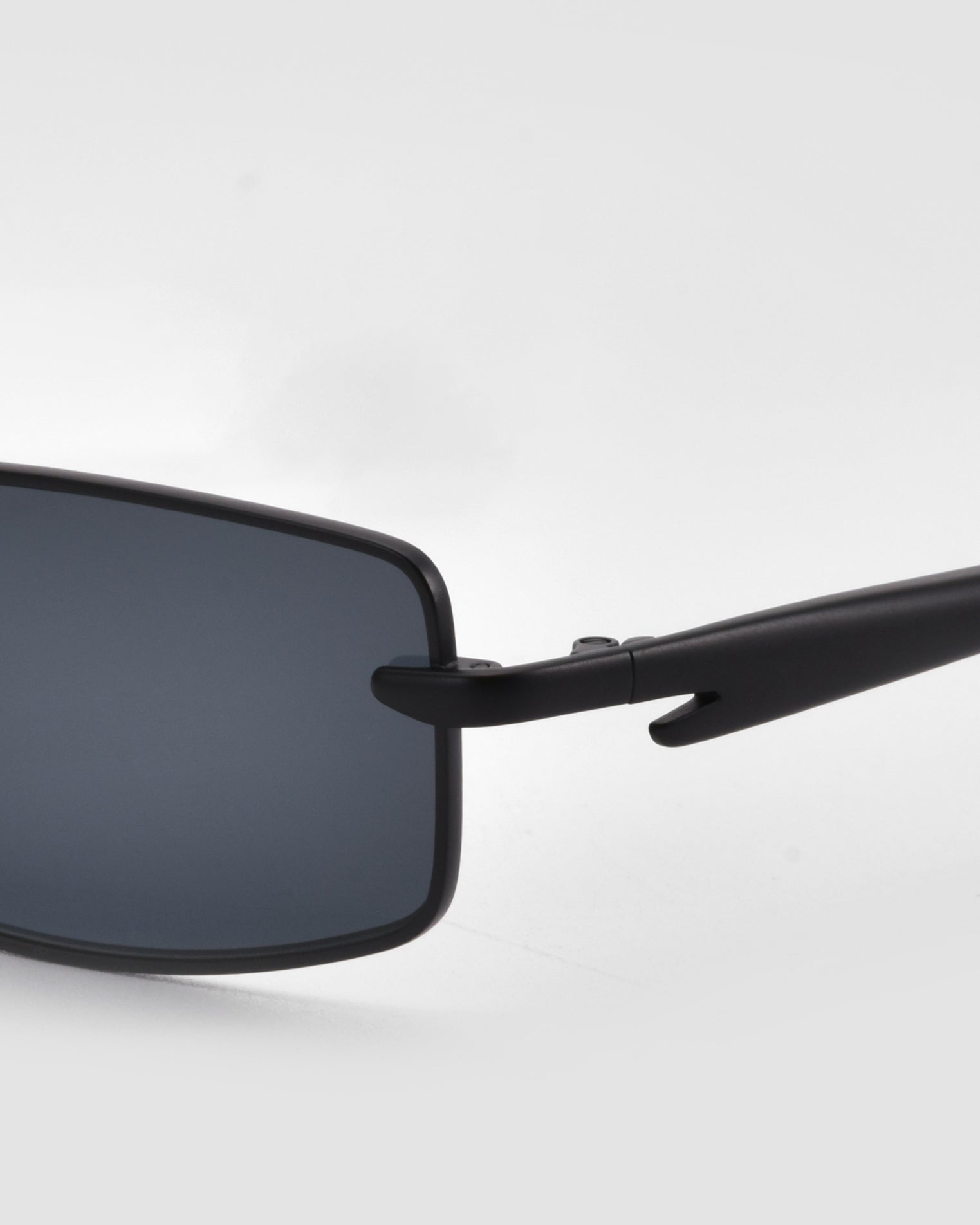Close-up of For Art&#39;s Sake® Lucio sunglasses, highlighting the sleek rectangular design with dark lenses and the left temple against a plain light gray background.
