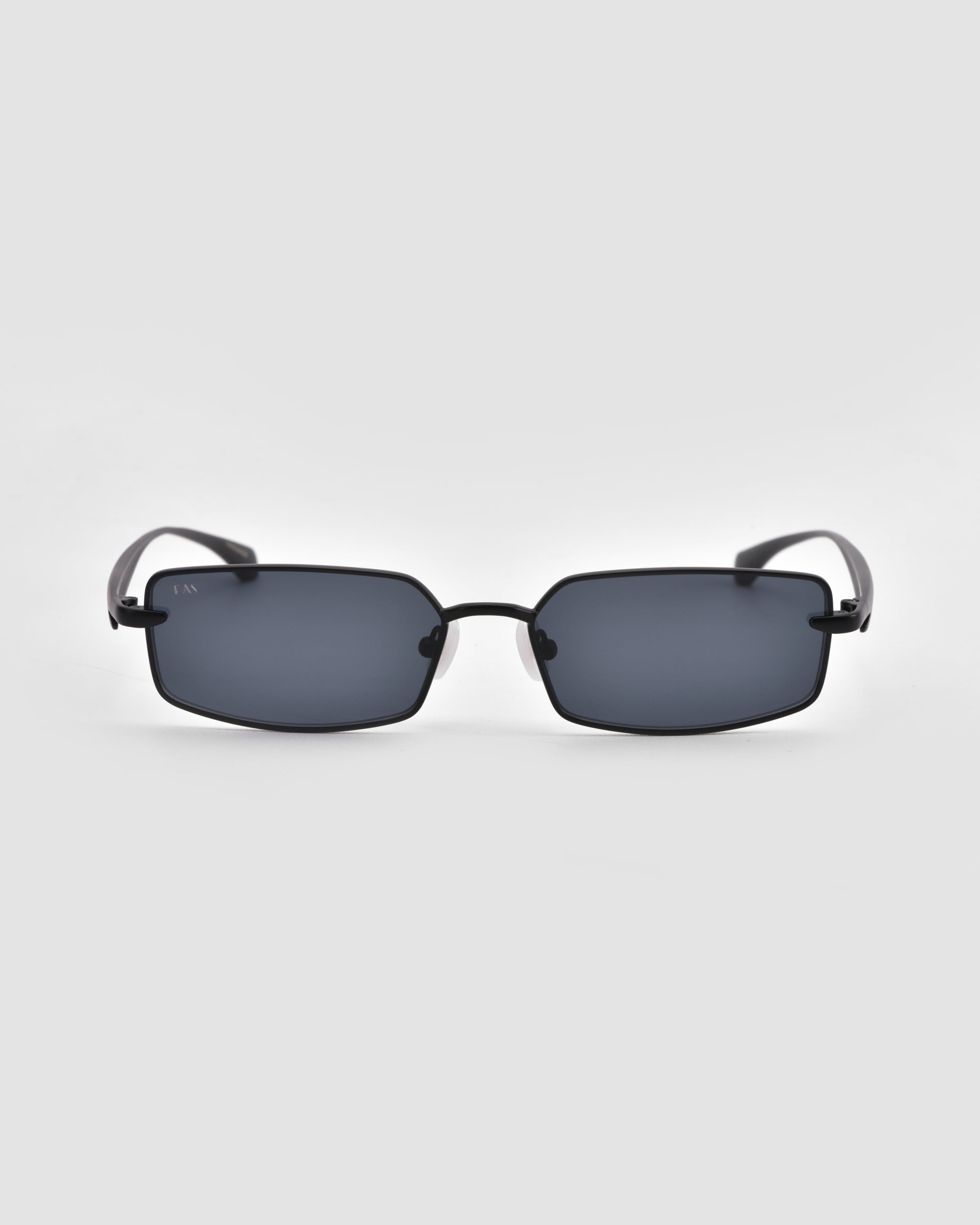 The Lucio sunglasses by For Art's Sake® feature a rectangular black frame with dark tinted lenses and a sculpted design, displayed face-on against a plain light gray background.