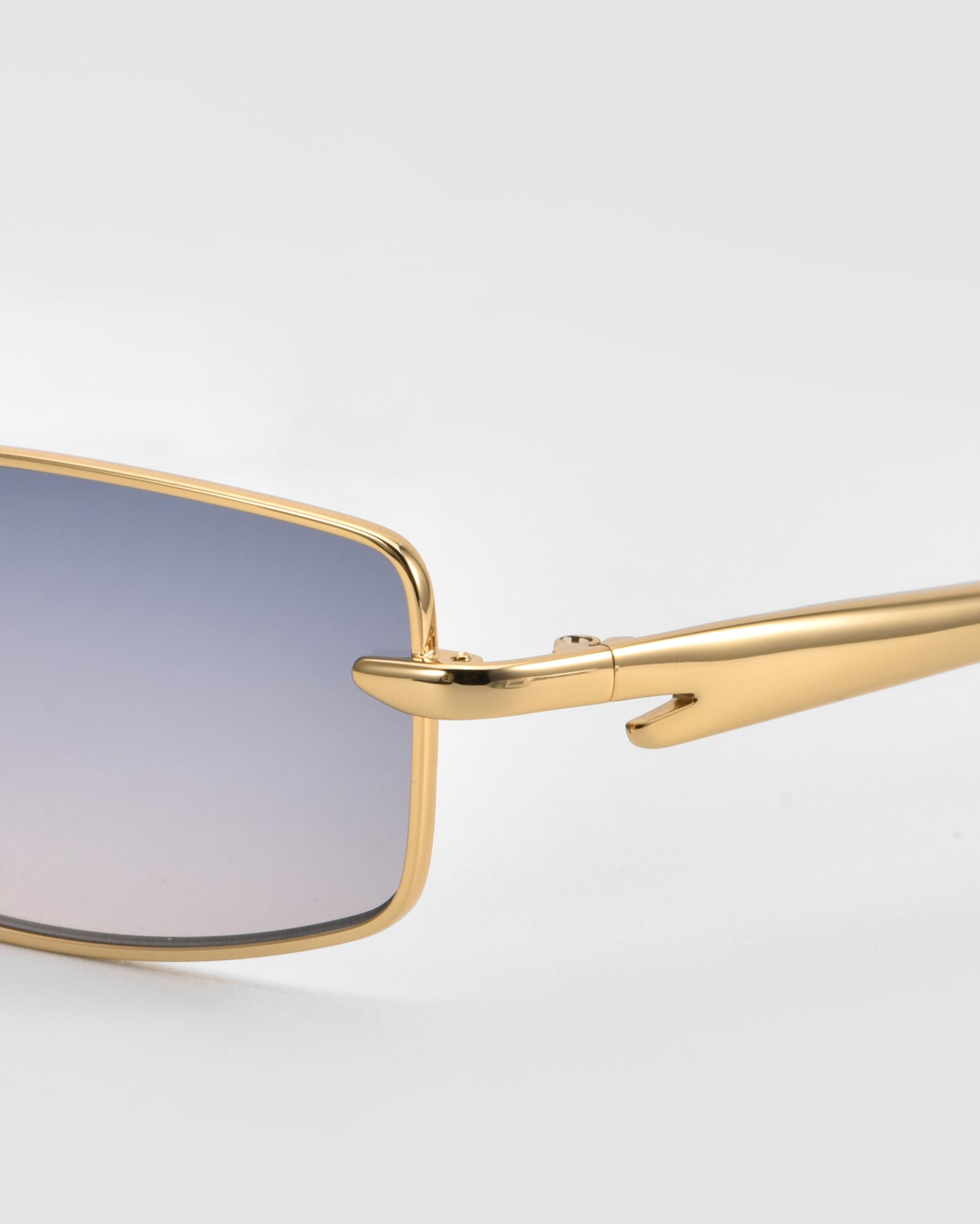 Close-up of For Art&#39;s Sake® Lucio sunglasses: sleek rectangular gold frames, gradient blue-tinted lenses, and shiny gold temples, set against a plain light gray background.