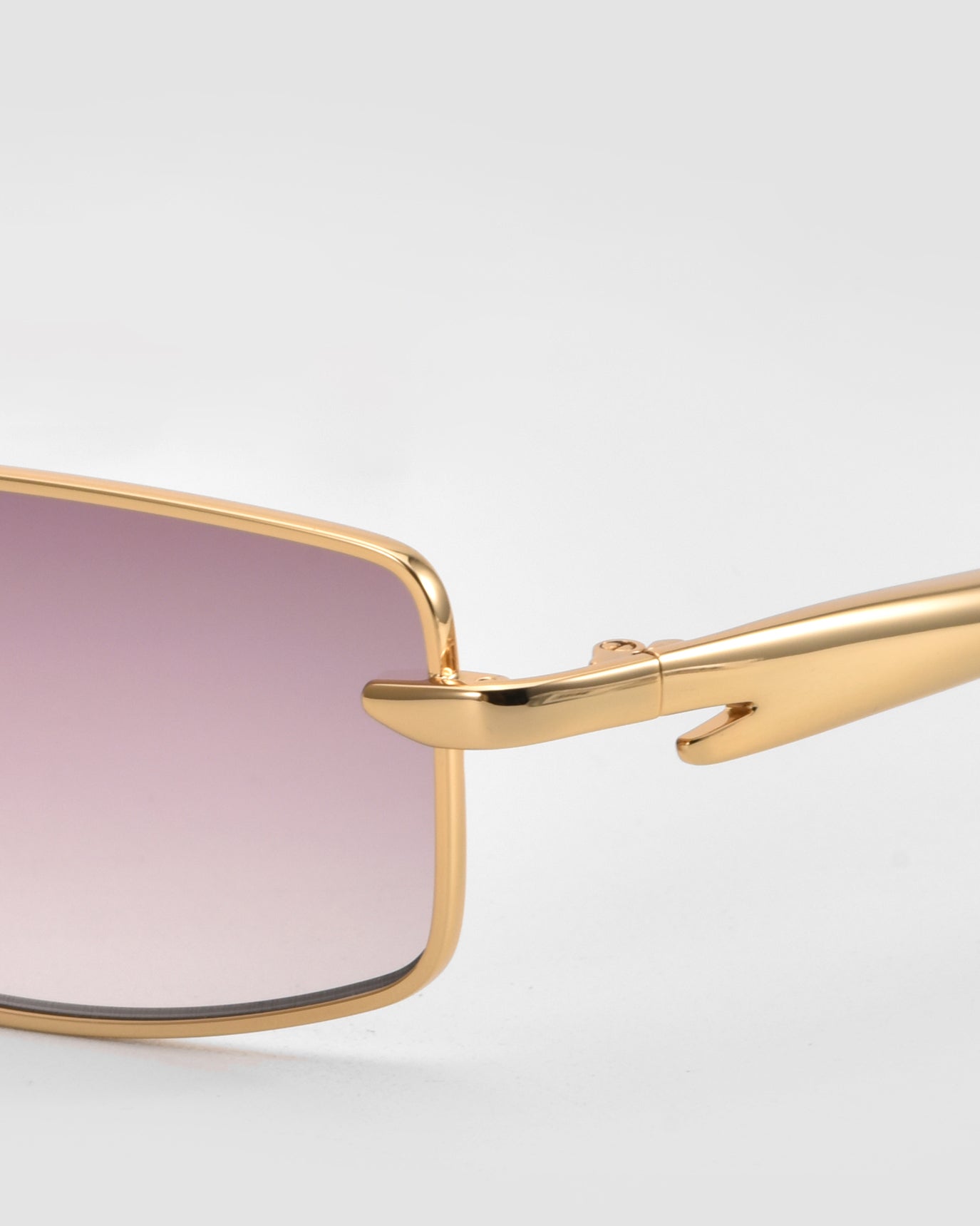 Close-up of For Art&#39;s Sake® Lucio sunglasses featuring a sleek gold frame and gradient pink rectangular lenses, set against a light gray background.