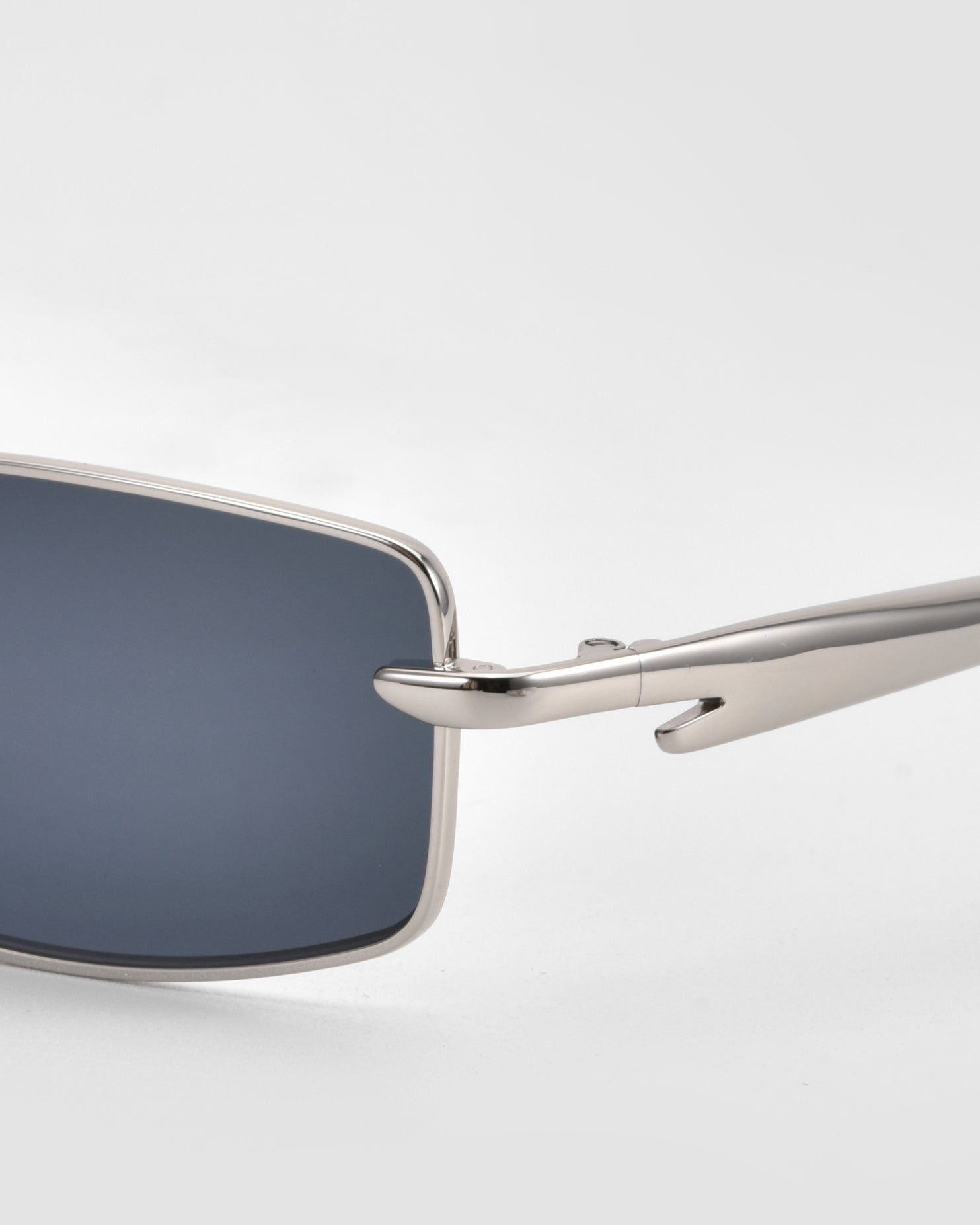 Close-up of For Art&#39;s Sake® Lucio sunglasses with a sleek silver metal frame and arms, plus rectangular dark lenses, set against a plain light background.