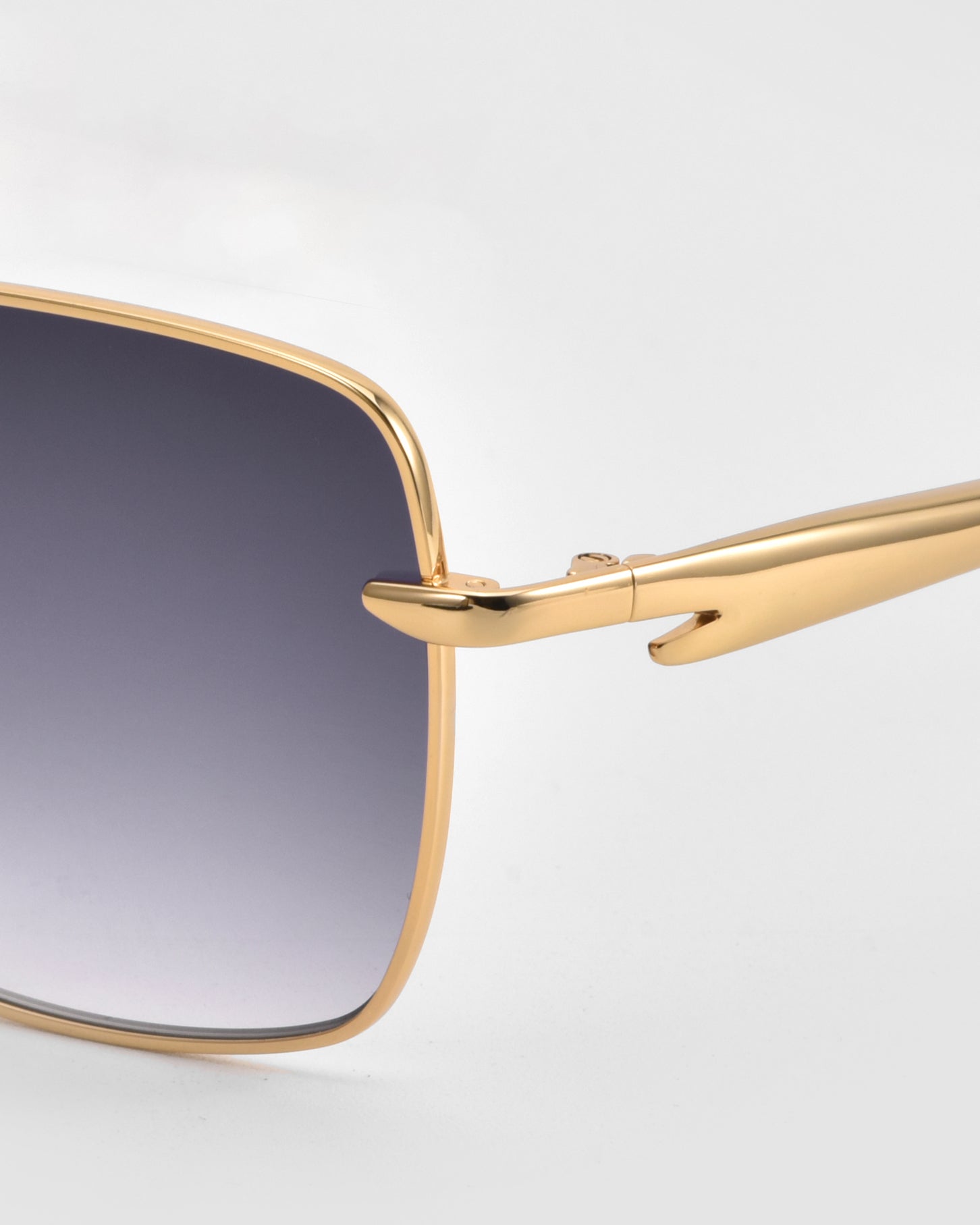 Close-up of the Edge sunglasses by For Art&#39;s Sake® featuring gold metal frames, gradient dark lenses, and detailed hinge and temple arms. The minimalist square silhouette is displayed against a light gray background.