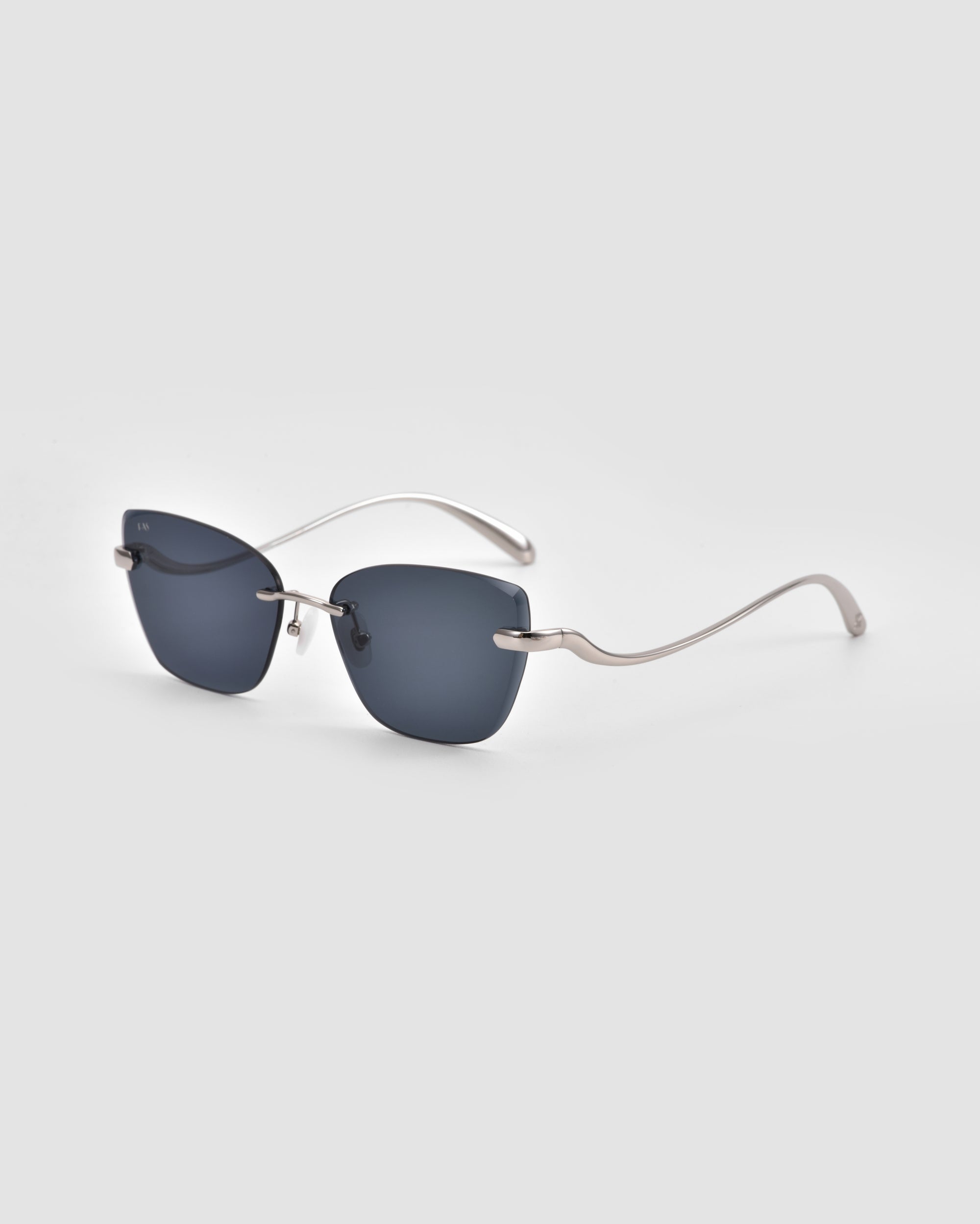 The For Art's Sake® Spark sunglasses feature rimless, dark square lenses and thin silver metal arms with a subtle 3D sculptural curve, showcased on a light gray background.