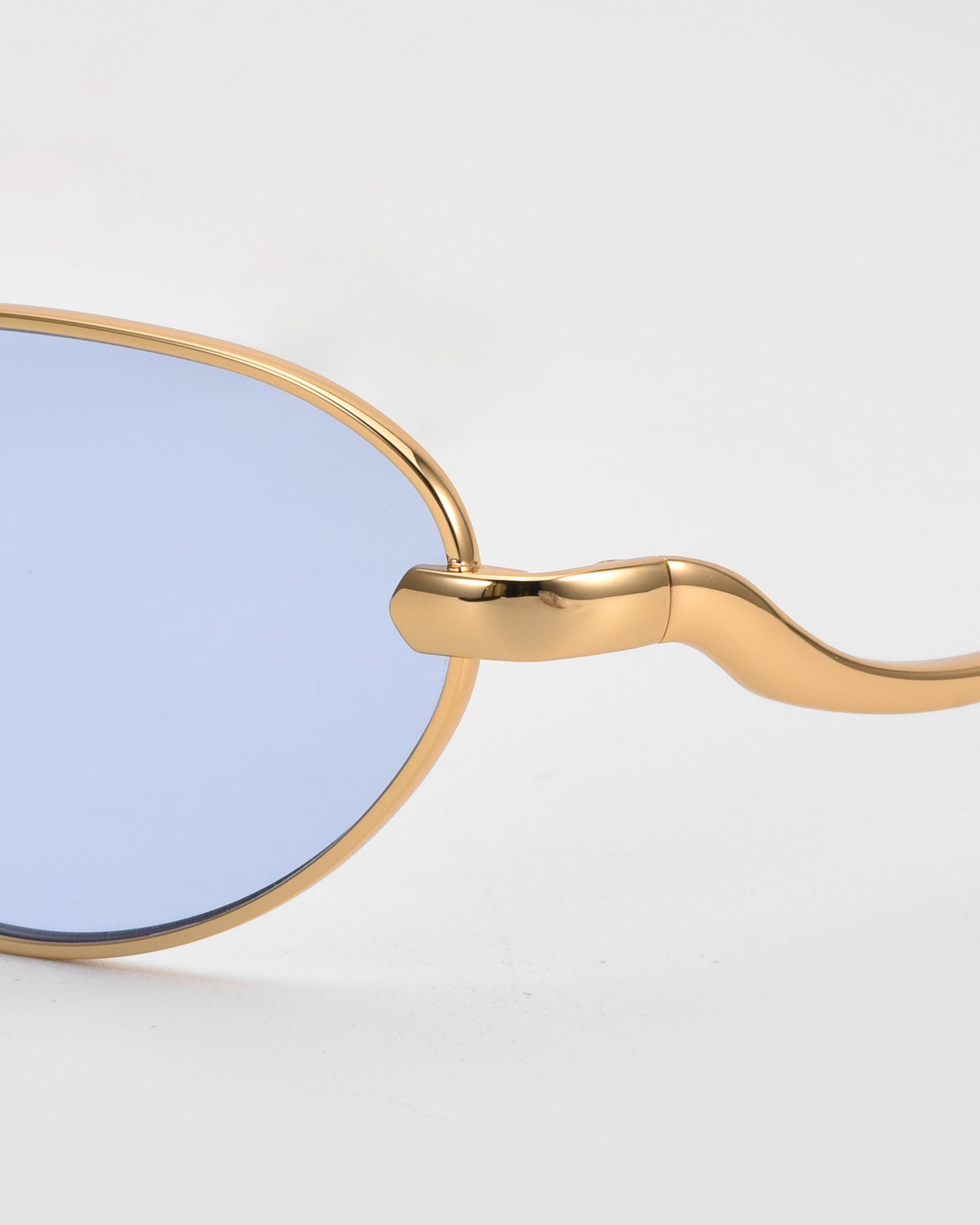 Close-up of For Art&#39;s Sake® Rebirth sunglasses featuring gold sculptural frames and blue tinted lenses, highlighting the side arm and hinge details against a plain white background.