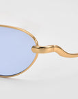 Close-up of For Art's Sake® Rebirth sunglasses featuring gold sculptural frames and blue tinted lenses, highlighting the side arm and hinge details against a plain white background.
