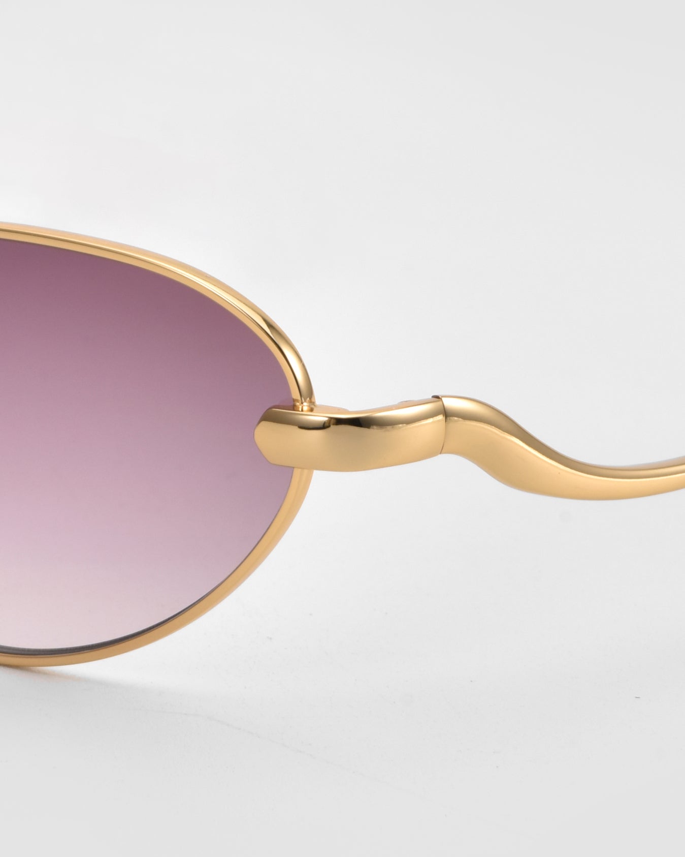 Close-up of For Art&#39;s Sake® Rebirth sunglasses with a sculptural gold metal frame, wavy temples, and purple-tinted lenses, set against a light gray background—a timeless statement accessory.