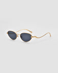 The For Art’s Sake® Rebirth sunglasses feature oval dark lenses and thin, gold 3D sculptural frames, elegantly displayed on a plain light gray background.