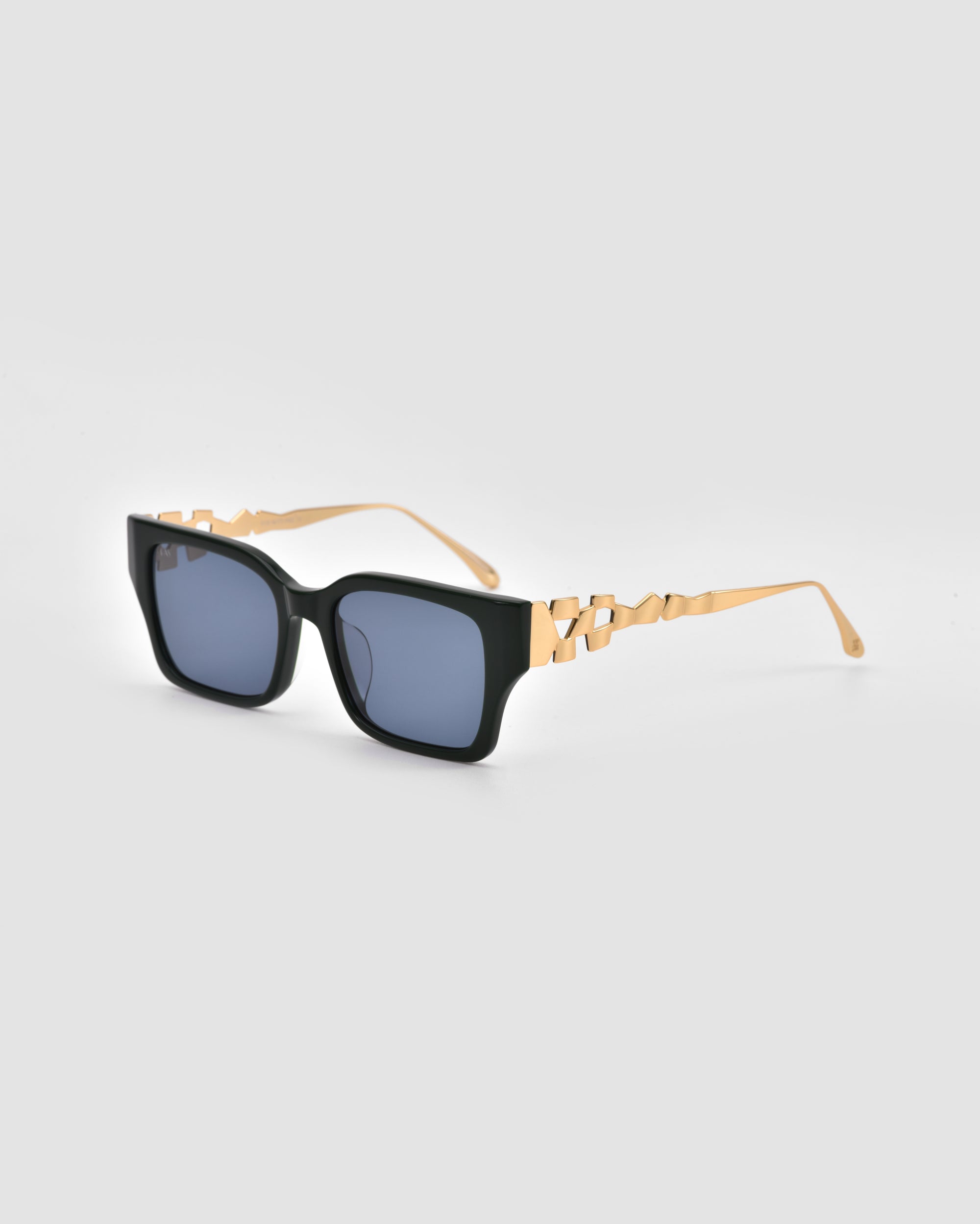 For Art's Sake® Incomplete: Rectangular black boxy sunglasses with dark lenses and gold arms featuring an interlocking mosaic metal design, shown against a light grey background.