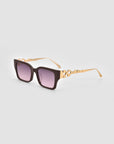 The For Art's Sake® Incomplete sunglasses feature large rectangular dark purple lenses, thick black frames, and gold arms with a detailed mosaic metal design, shown on a plain light gray background.