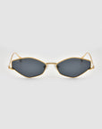 The Moment sunglasses by For Art's Sake® feature gold frames with a geometric cat-eye design and dark lenses, shown facing forward on a plain light gray background.