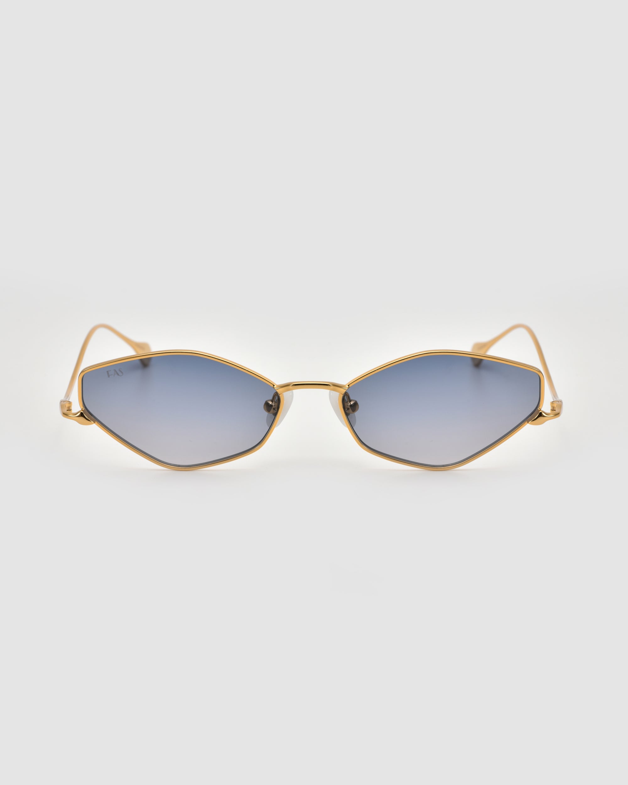 The Moment sunglasses by For Art's Sake® feature a geometric silhouette with gold metal frames and blue-tinted lenses, showcased on a plain light gray background.