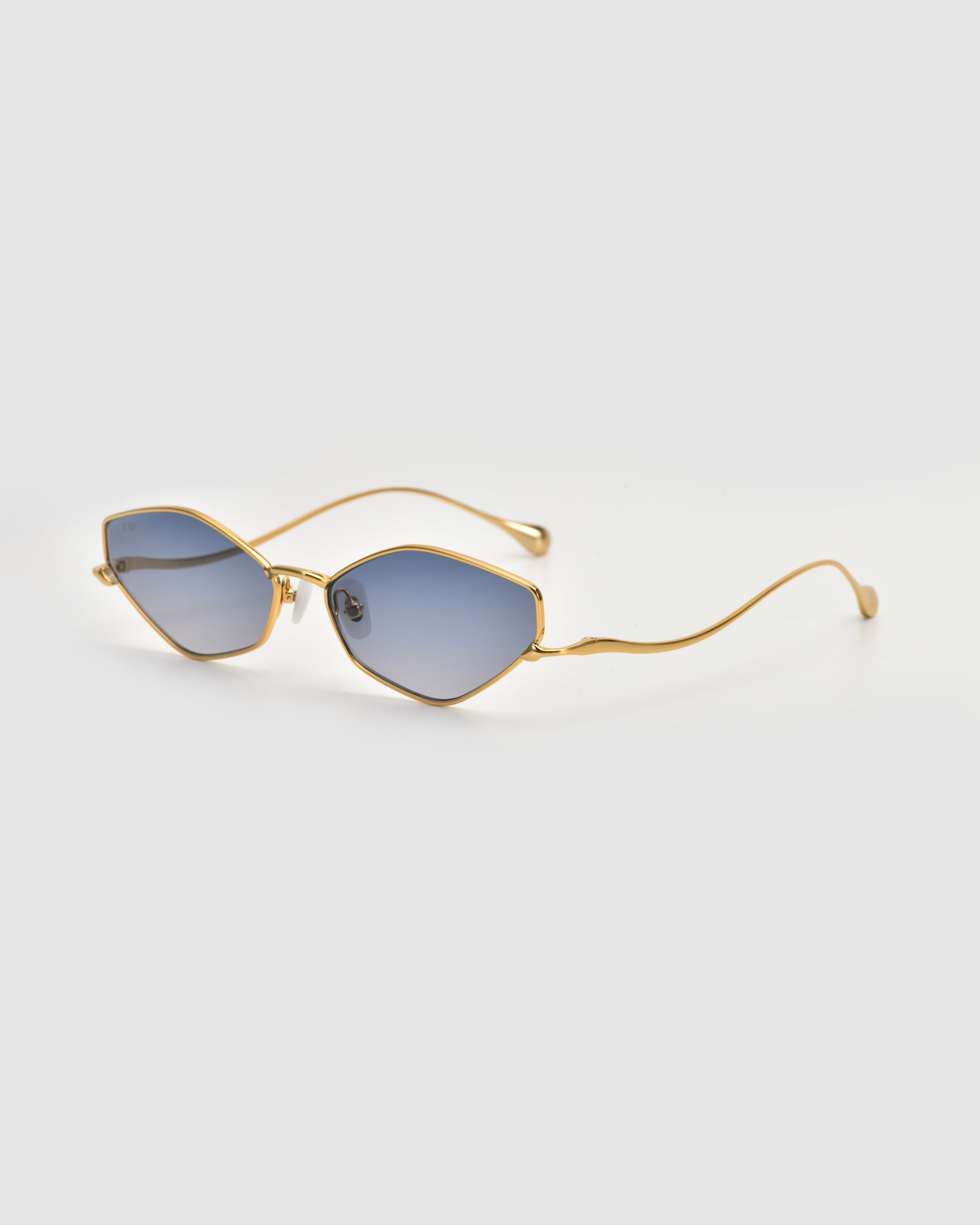 The Moment sunglasses by For Art's Sake® feature a thin metal frame and blue-tinted, cat-eye geometric lenses, shown against a plain light gray background.