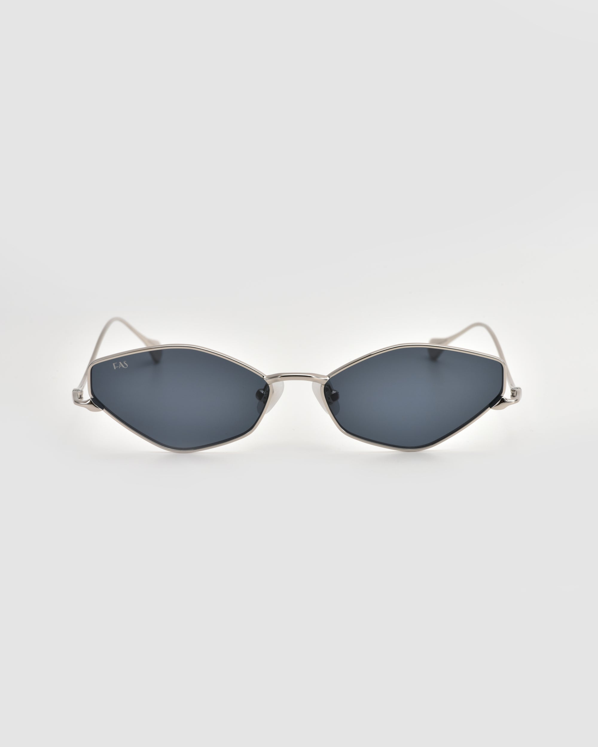 The Moment sunglasses by For Art's Sake® feature a sleek metal frame with silver accents and angular dark lenses, shown facing forward on a light gray background.