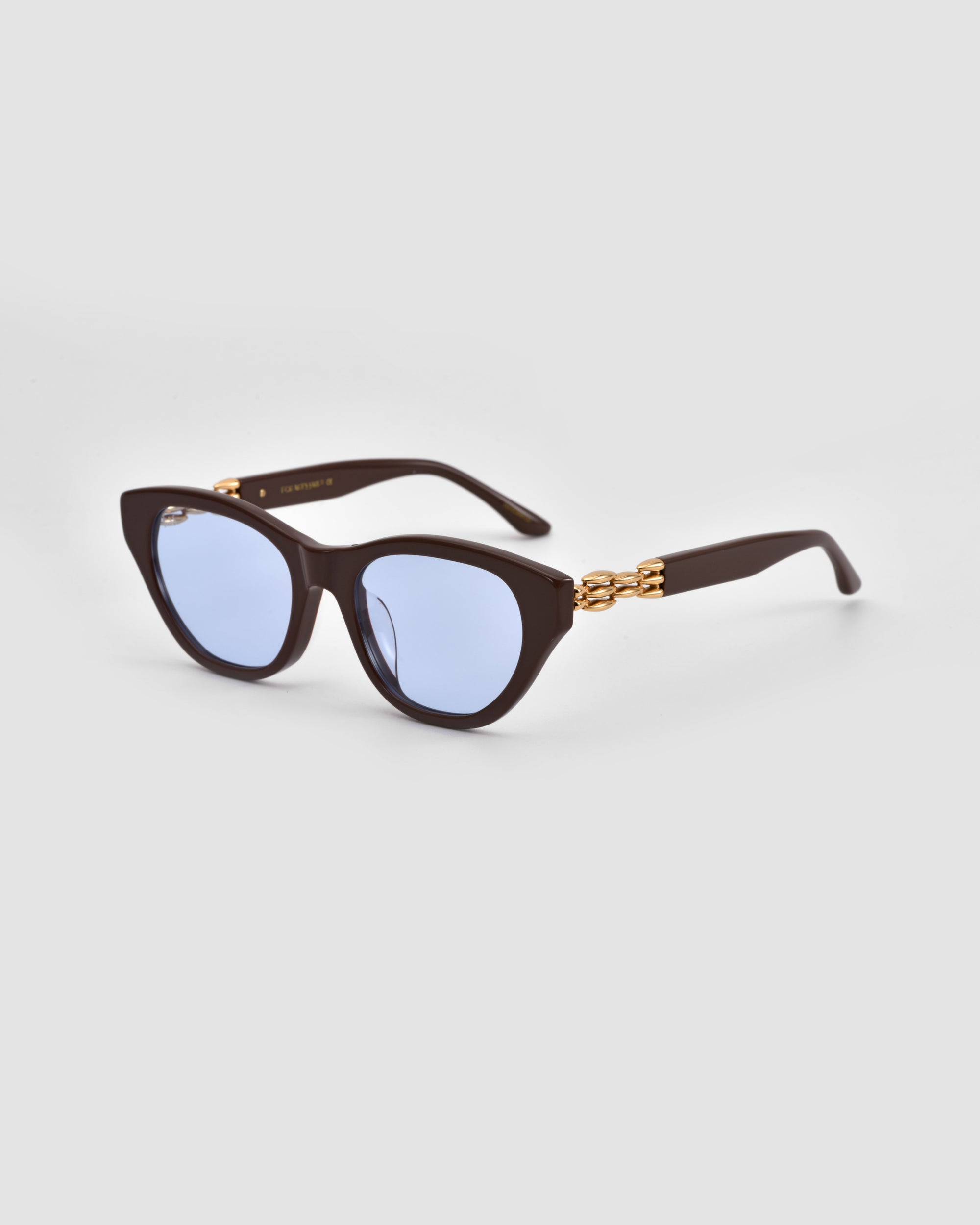 For Art's Sake® The Cuts cat-eye sunglasses feature blue-tinted lenses and 3D weaved metal gold chain arms, shown on a light gray background.