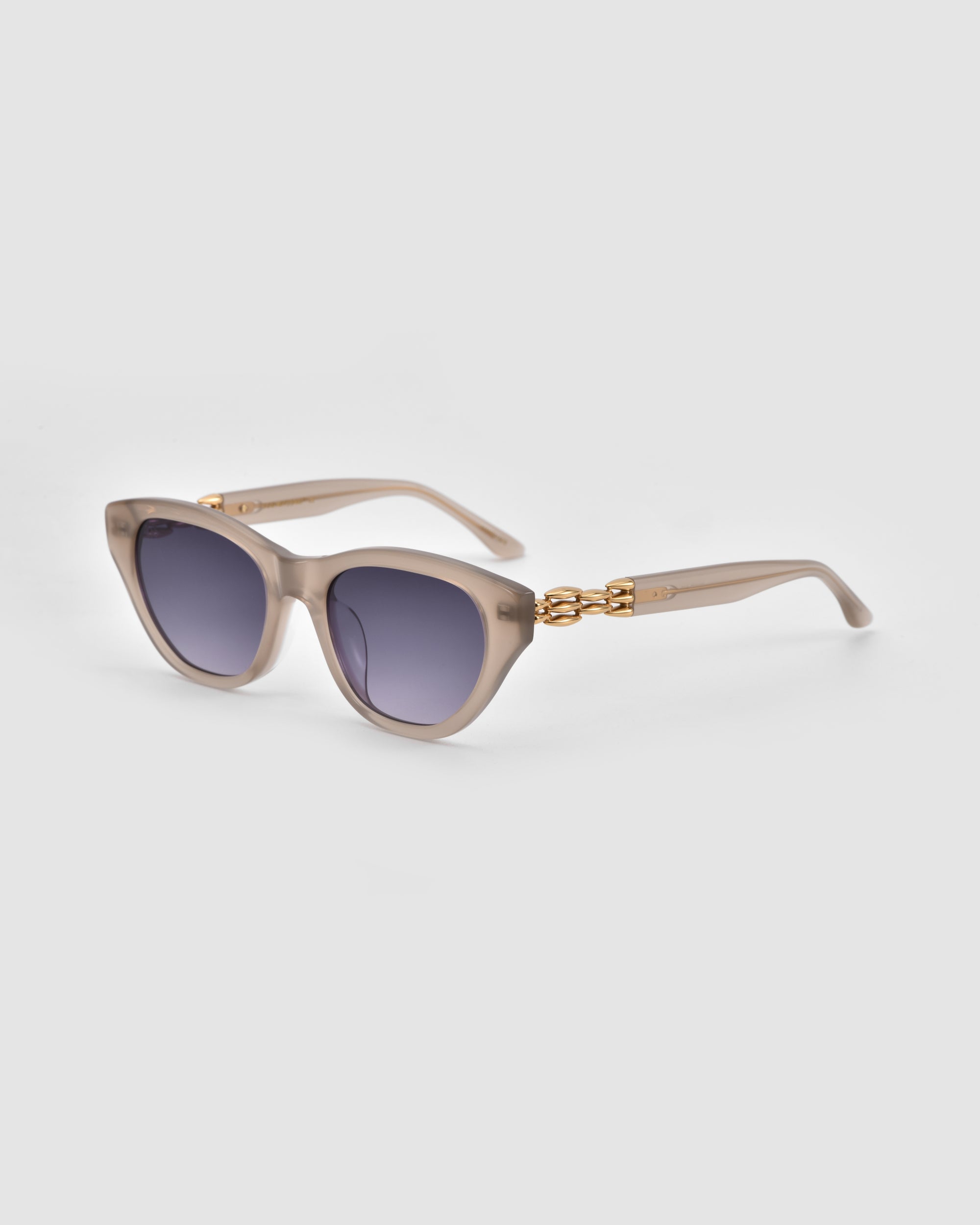 The Cuts by For Art's Sake® are beige square cat-eye sunglasses featuring dark gradient lenses and 3D weaved gold chain detailing on the temples, shown on a light grey background.