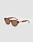 The Cuts sunglasses by For Art's Sake® feature a tortoiseshell sculptural frame, round brown lenses, and gold chain accents on the arms, shown against a plain light gray background.
