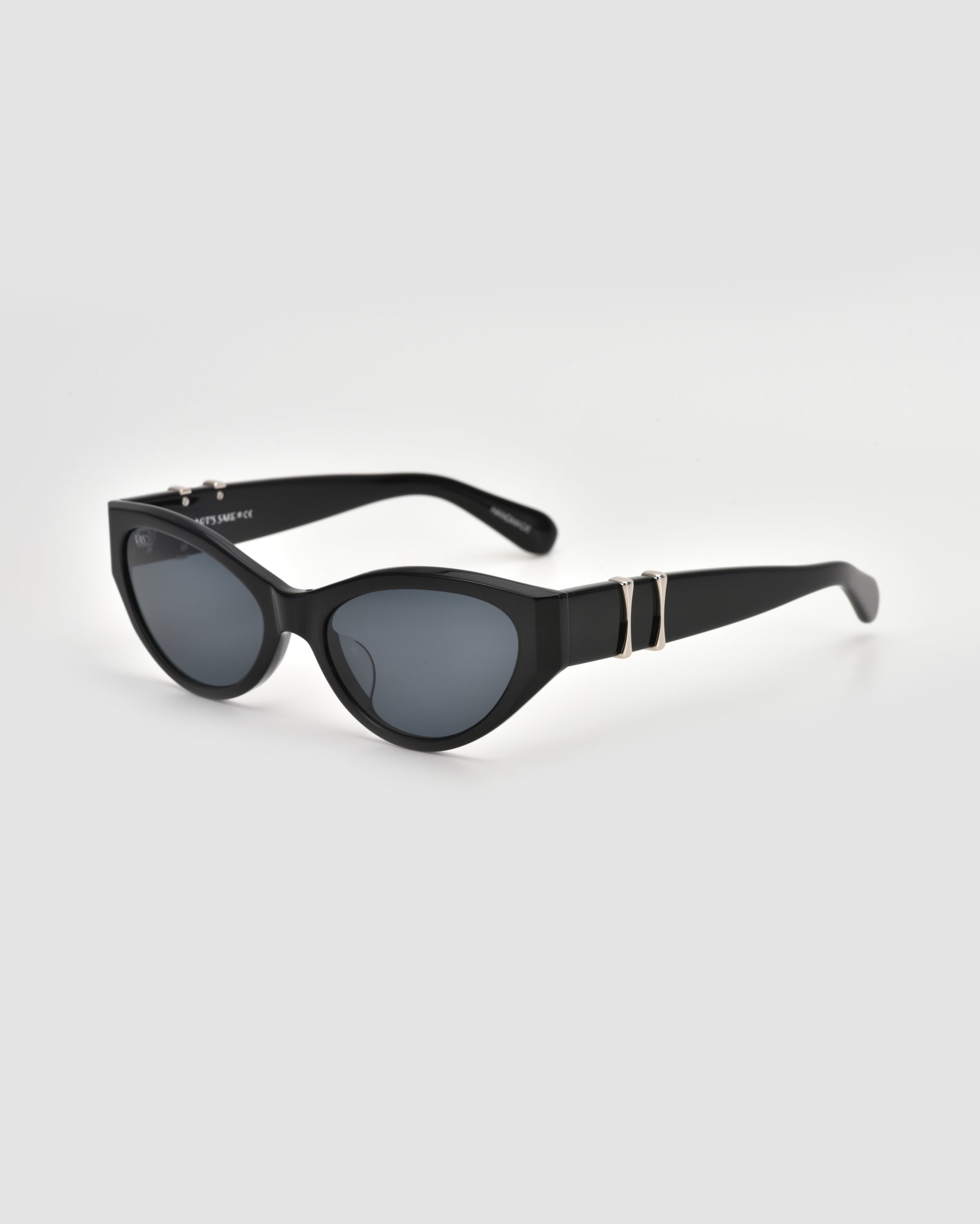 For Art's Sake® Halo(S) black cat-eye sunglasses feature dark lenses, a sculptural acetate frame, and gold accents on the temples, shown against a plain white background.