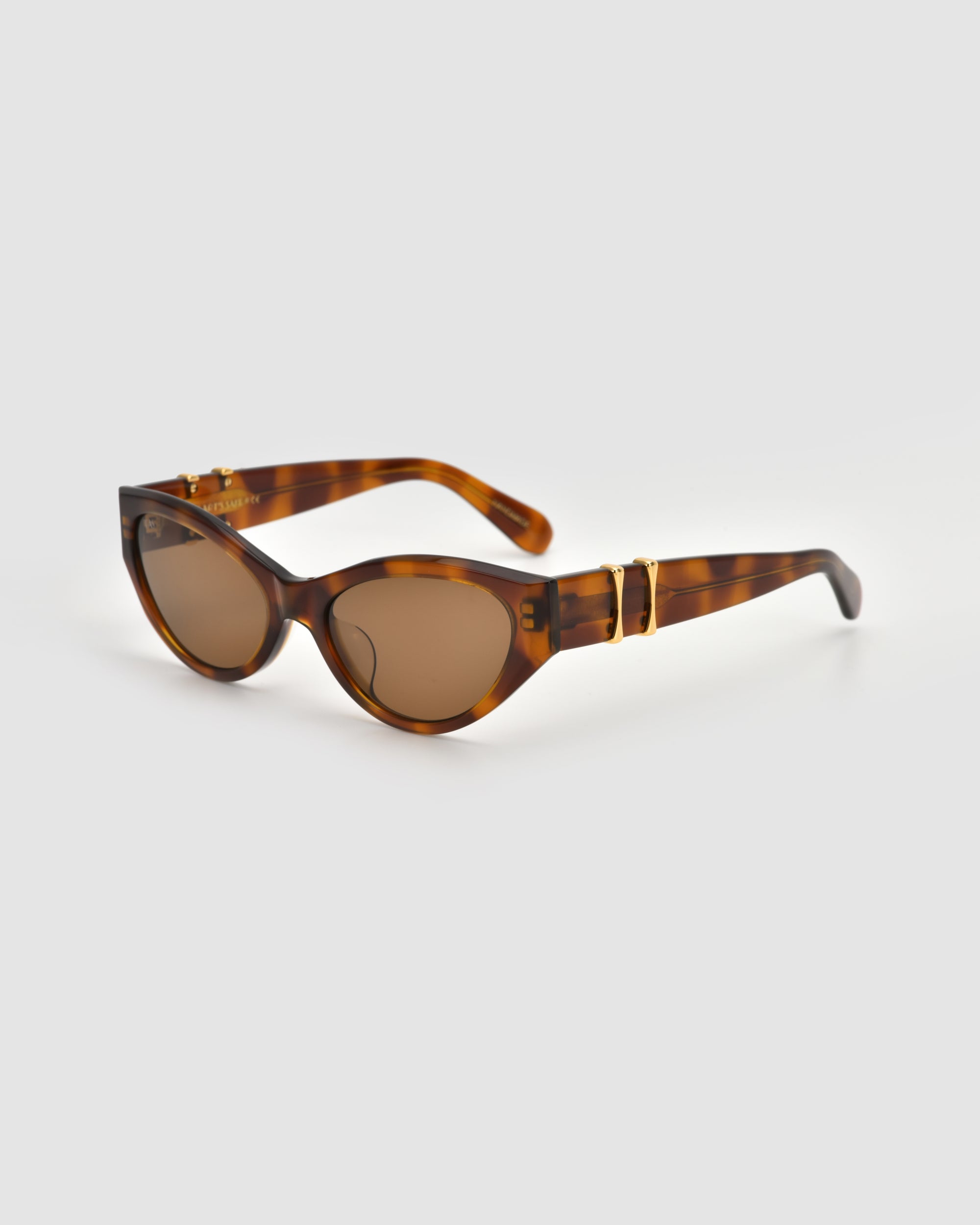 The For Art's Sake® Halo(S) sunglasses feature a brown tortoiseshell cat-eye design with gold temple accents and a sculptural acetate frame, displayed on a light grey background.