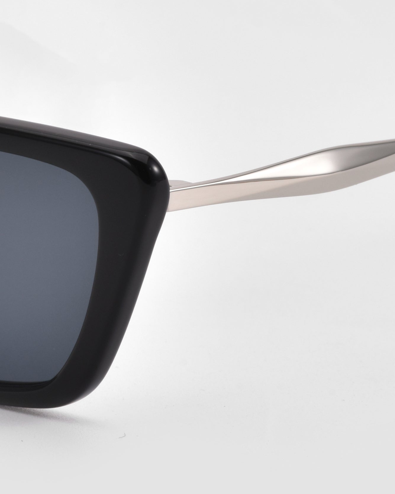 Close-up of the left side of Harmony(S) sunglasses by For Art&#39;s Sake®, showing a black rectangular sculptural frame with a sleek silver metal arm, set against a plain white background.