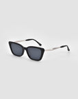 The Harmony(S) sunglasses by For Art's Sake® are black rectangular minimal shades with a sculptural frame, dark lenses, and slim metallic arms, shown on a plain light gray background.