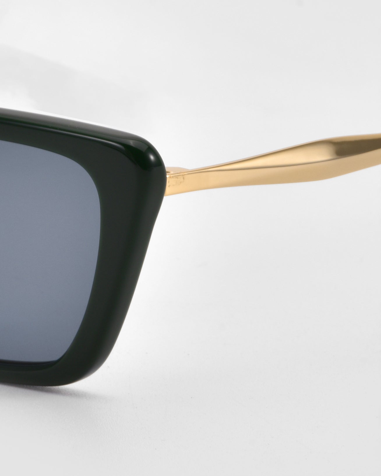 Close-up of the For Art&#39;s Sake® Harmony(S) sunglasses, featuring a minimal black sculptural frame, blue-tinted lens, and gold-colored temple arm, set against a plain white background.