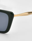 Close-up of the For Art's Sake® Harmony(S) sunglasses, featuring a minimal black sculptural frame, blue-tinted lens, and gold-colored temple arm, set against a plain white background.