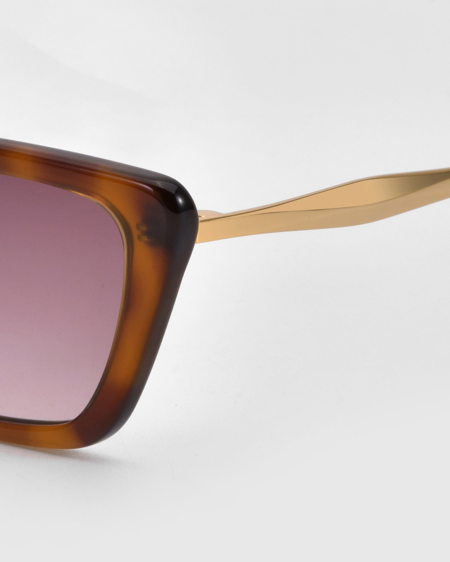 Close-up of For Art&#39;s Sake® Harmony(S) sunglasses with a brown square sculptural frame, gradient pink lenses, and gold-colored arms, set against a plain white background.