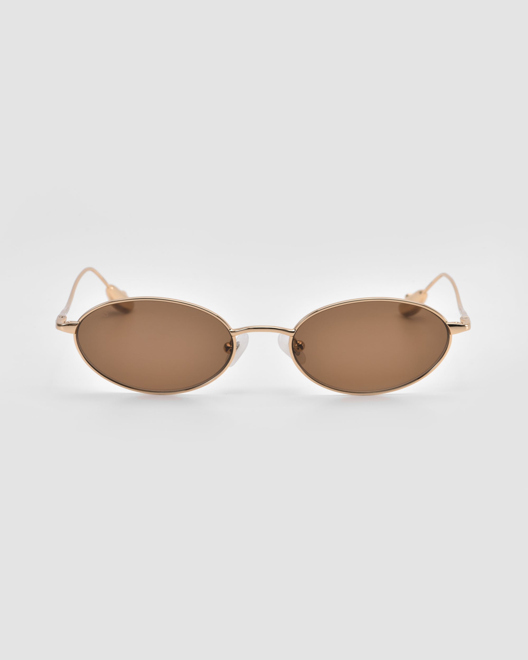 For Art's Sake® Calla I: lightweight, modern oval metal glasses with thin gold frames and brown tinted lenses, showcased on a plain light grey background.