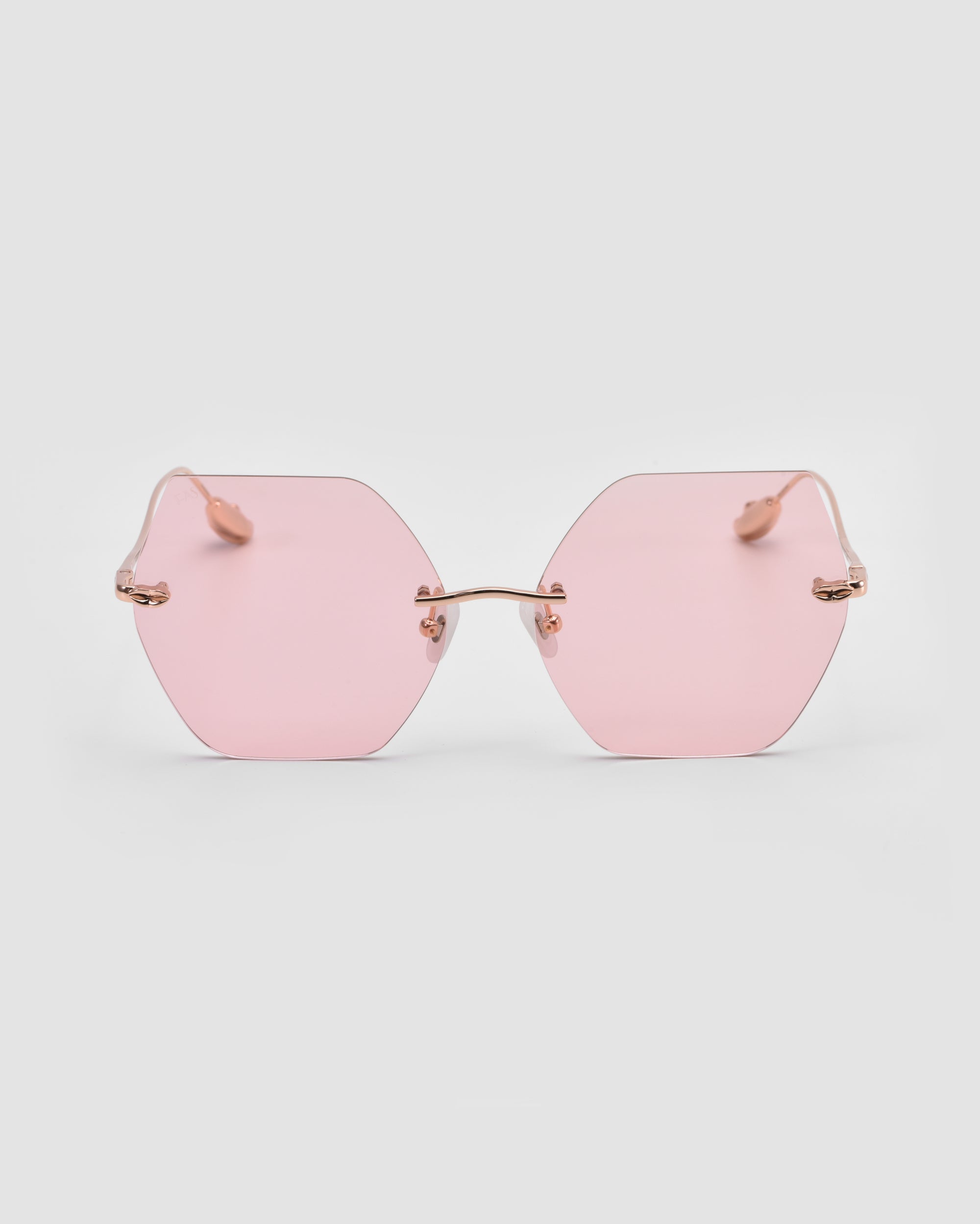 For Art's Sake® Georgia sunglasses feature a hexagonal shape, pink-tinted lenses, and a thin gold metal frame with sculpted temples, shown against a plain white background.
