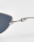 Close-up of the side of For Art's Sake® Lake cat-eye sunglasses, showing sculpted temples with a silver metal frame and dark tinted lens set against a plain white background.