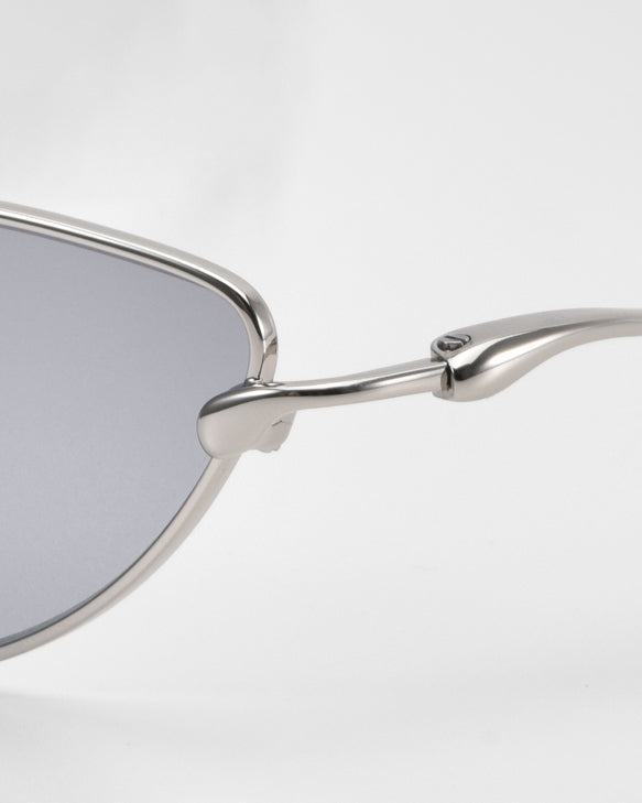 Close-up side view of For Art's Sake® Lake cat-eye sunglasses featuring a silver metal frame, gray lenses, sculpted temples, and hinge detail against a plain white background.