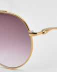 Close-up of the right lens and gold metal frame of For Art’s Sake® Lines oversized aviator sunglasses with a gradient purple tint and sculpted temples, set against a plain light background.