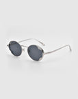 For Art's Sake® Leaf II sunglasses with round silver metal frames and dark lenses, angled on a plain light gray background.