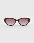 Front view of For Art's Sake® Tulip I sunglasses with bold sculptural burgundy cat-eye acetate frames, gradient purple lenses, and slim gold temples, displayed on a plain light gray background.