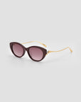 The Tulip I cat-eye sunglasses by For Art's Sake® feature a bold acetate front, dark purple frames, gold metal arms, and gradient purple lenses, showcased against a light gray background.