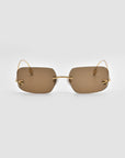 The For Art's Sake® Magnolia sunglasses are rectangular, designer frameless shades with brown tinted lenses and slim gold temples, shown on a plain light gray background.