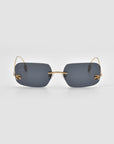 For Art's Sake® Magnolia frameless rectangular sunglasses feature dark gray lenses and thin gold arms, shown on a plain light gray background.