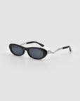 For Art's Sake® Abstraction I sunglasses: black oval frames with dark lenses, bold temple design, and sculptural silver zigzag metal arms, shown on a light gray background.