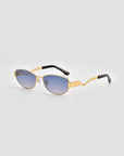 For Art's Sake® Abstraction II sunglasses feature a gold geometric metal frame, blue-tinted lenses, and black arm tips, set against a light grey background.