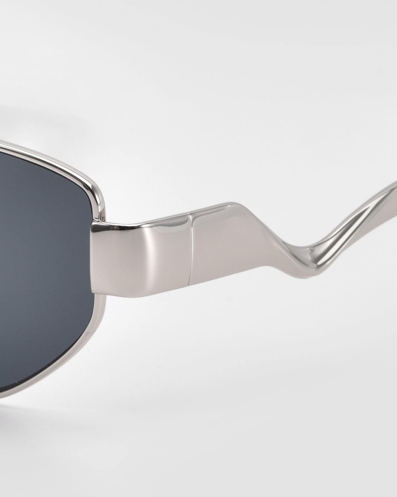 Close-up of For Art's Sake® Abstraction II sunglasses featuring a silver geometric metal frame, dark lenses, and distinctively curved, shiny temples against a plain light background.